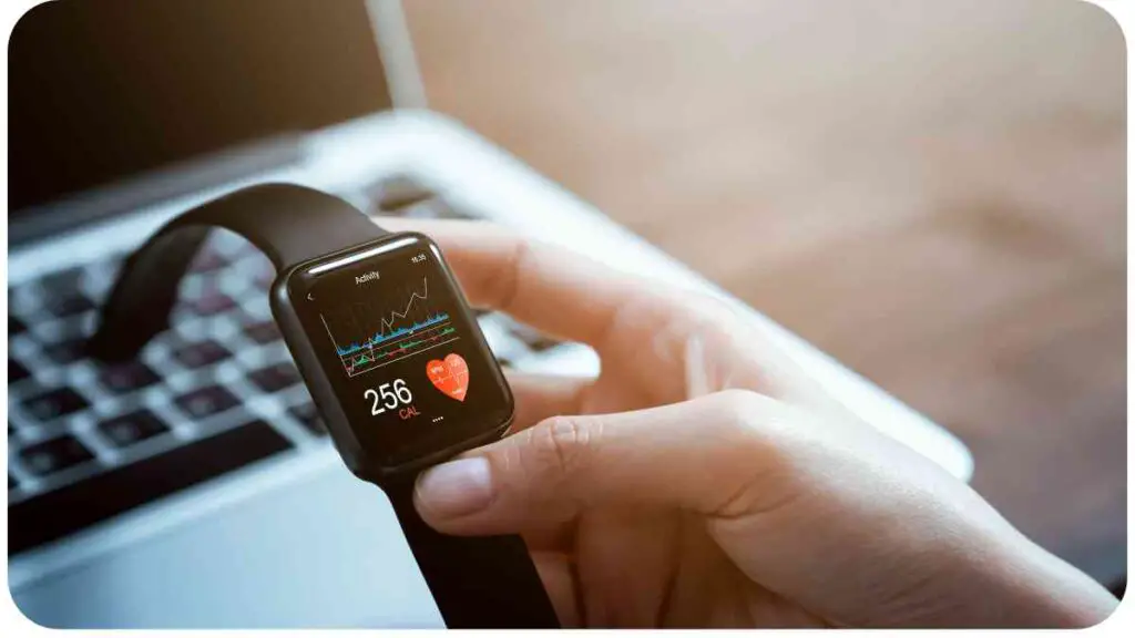 a person holding a smart watch next to a laptop